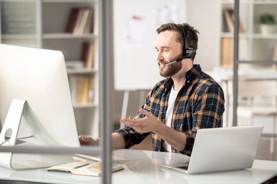 Aareon-Hotlines: Junger Mann mit Headet an Schreibtisch sitzend
